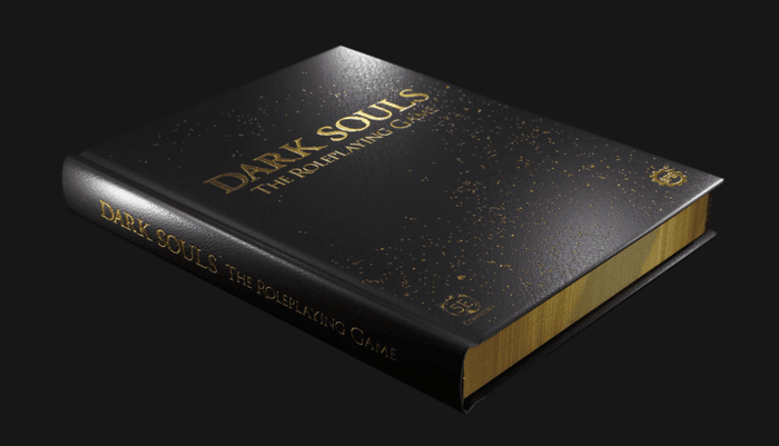 Opis obrazka: zdjęcie przedstawia limitowaną edycję podręcznika do Dark Souls. Czarna, gruba okładka posiada złote akcenty oraz błyszczące boki w złotym kolorze.