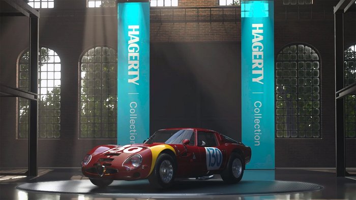 Opisujemy: tylna ściana garażu zbudowanego z cegieł. Na jej tle stoi jedno auto: czerwone, zabytkowe Porsche z numerem 130. W tle wiszą dwa niebieskie banery z napisem HAGERTY Collection.
