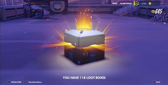 Na zdjęciu lśniący na pomarańczowo, czekający na otwarcie lootboks - srebrne pudełko z łupami - w grze Overwatch. Na dole napis "you have 118 loot boxes"